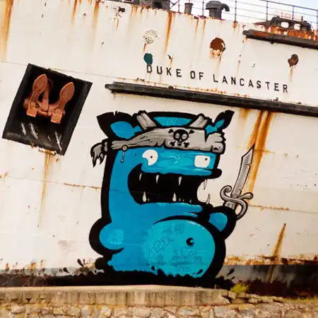 A blue cartoon monster with fangs wearing a pirate hat and holding a sword.