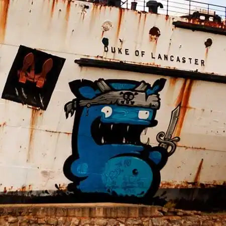 Blue cartoon monster with a sword painted as street art graffiti.