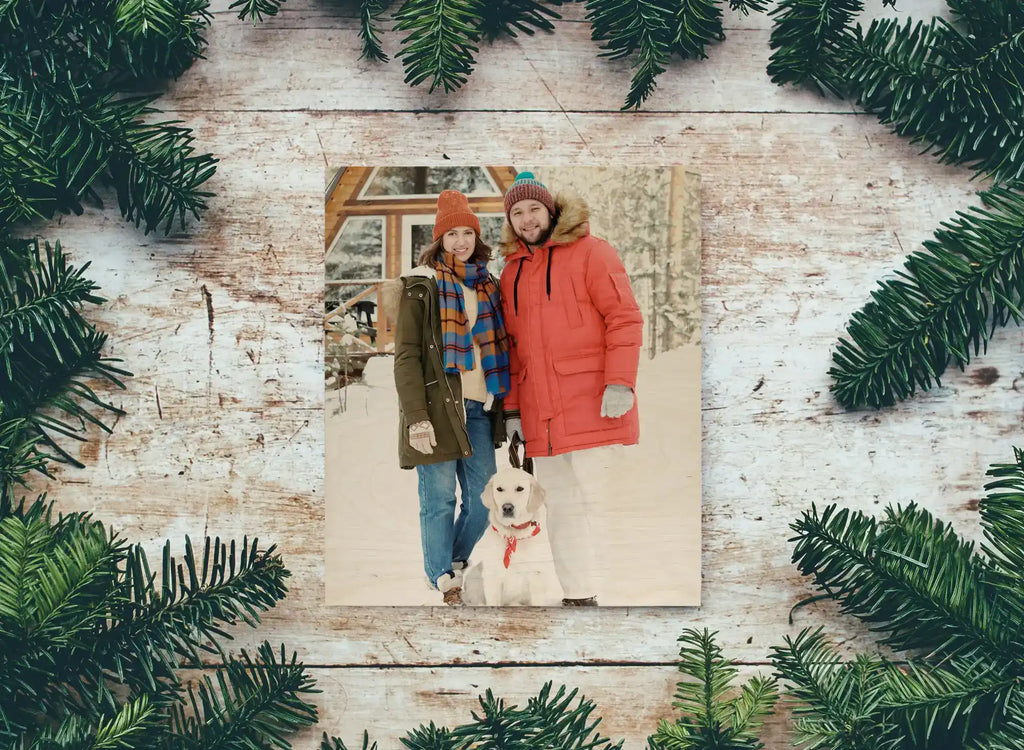 A photograph framed by evergreen branches on a whitewashed wooden surface.